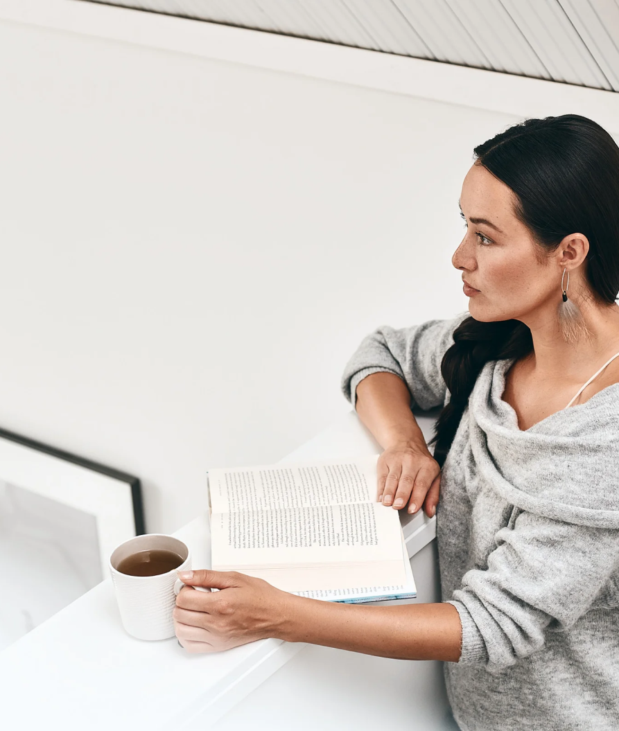 A young woman reading a book with a tea